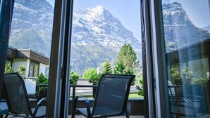Habitación con vistas a montañas nevadas. Se ven sillas y una mesa en primer plano.