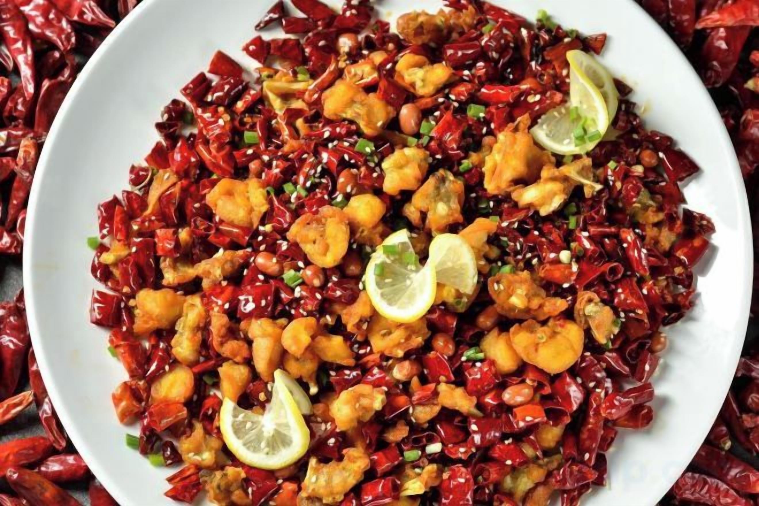 Un plato de comida con camarones y chiles rojos.