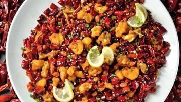 Un plato de comida con camarones y chiles rojos.