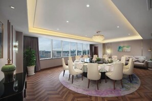 A modern dining area with a round table, chairs, and a city view. - Mingxing Conifer Hotel (Suining)