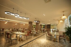 A modern dining area with multiple tables and chairs, geometric ceiling lights, and a herringbone floor pattern. - Mingxing Conifer Hotel (Suining)