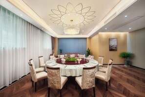 A dining area with a round table, chairs, and a chandelier.