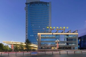 A modern hotel with a curved facade, a prominent entrance, and a tall adjacent building.
