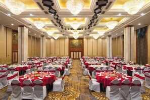 A banquet hall with rows of tables, each with a red tablecloth and white chairs, and a chandelier ceiling. - Mingxing Conifer Hotel (Suining)
