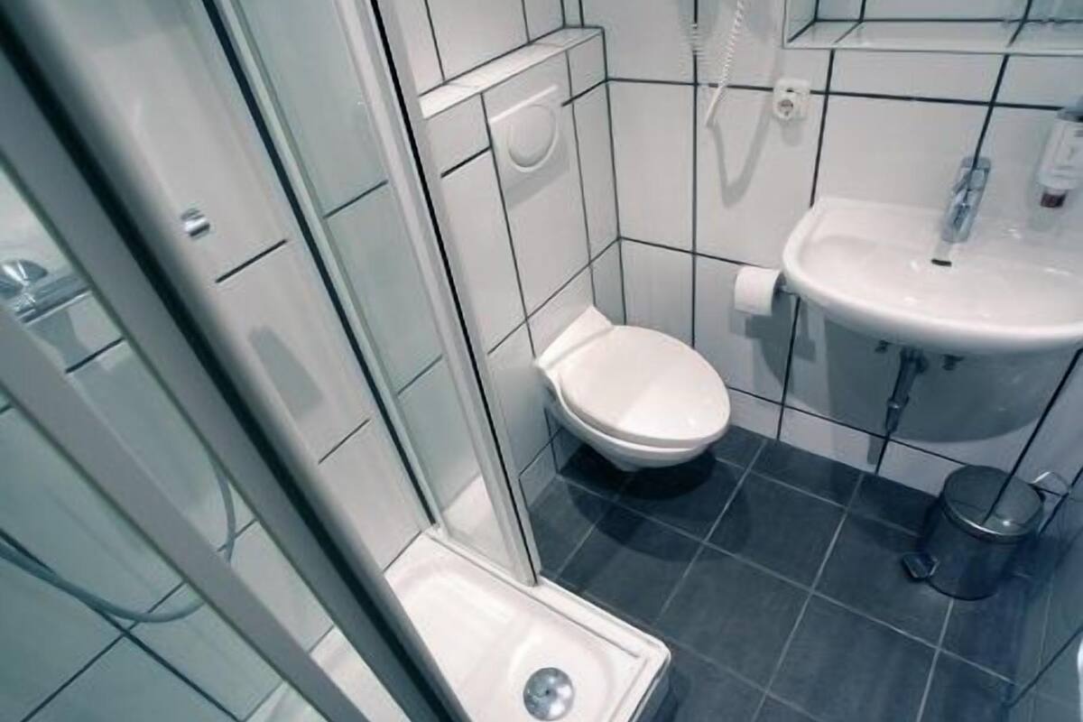A small, modern bathroom with a toilet, sink, and shower.