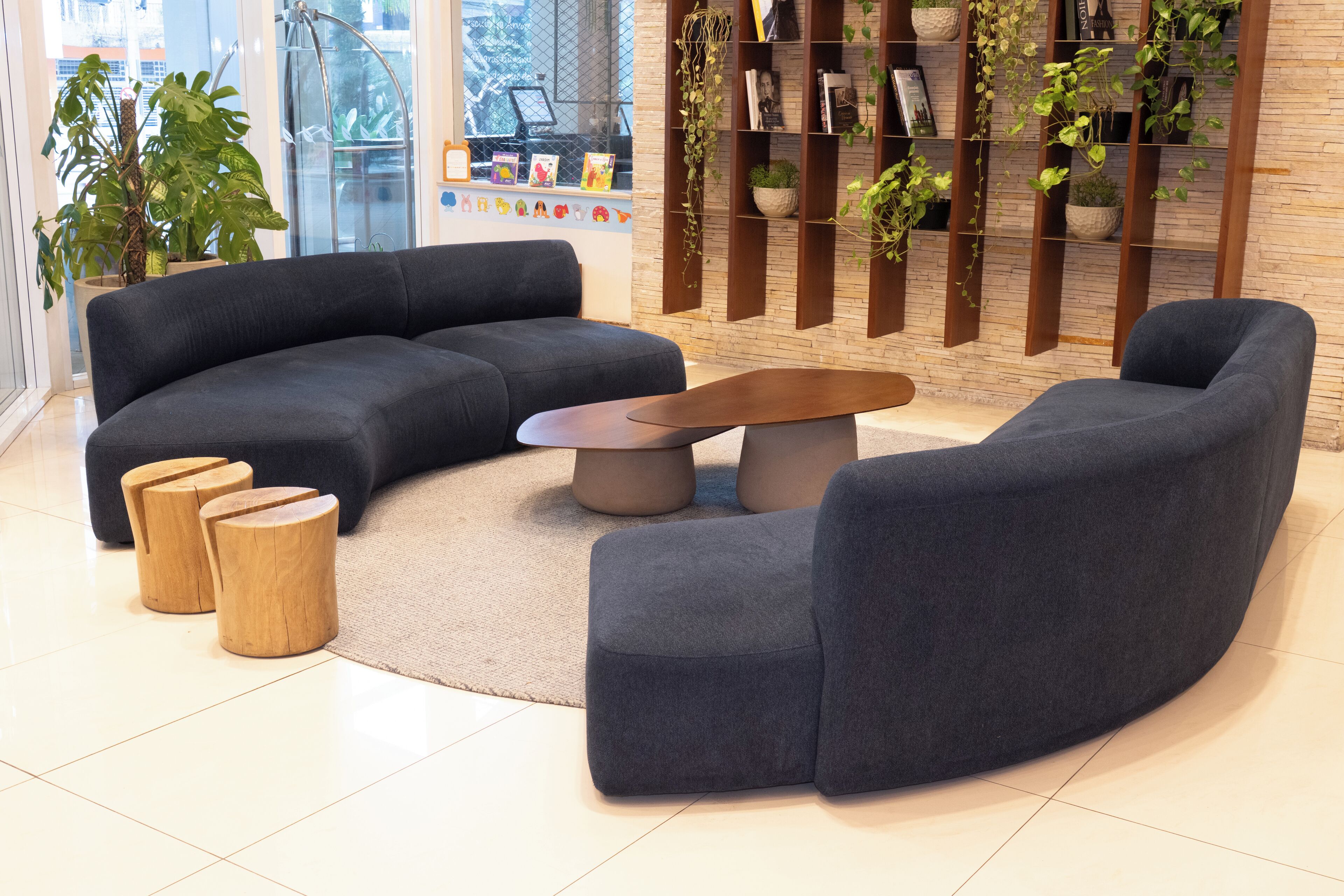 A modern living room with a sectional sofa, a coffee table, and wooden stools.