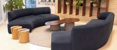 A modern living room with a sectional sofa, a coffee table, and wooden stools.