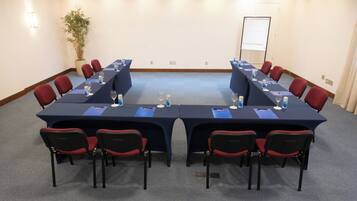 Ein Konferenzraum mit langem Tisch, roten Stühlen und einer Zimmerpflanze.