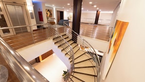 A spacious hotel lobby with a central staircase, a reception desk, and a large pillar. - Blue Tree Towers Caxias do Sul (Caxias do Sul)