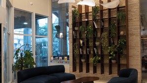 A modern lobby with a curved seating area, a tall plant wall, and pendant lighting. - Blue Tree Towers Caxias do Sul (Caxias do Sul)