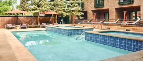 A swimming pool area with multiple pools, lounge chairs, and umbrellas.