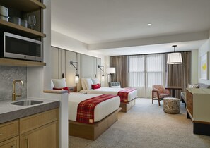Habitación de hotel con dos camas, un escritorio, una silla, un sofá, una lámpara, un microondas y un lavamanos.