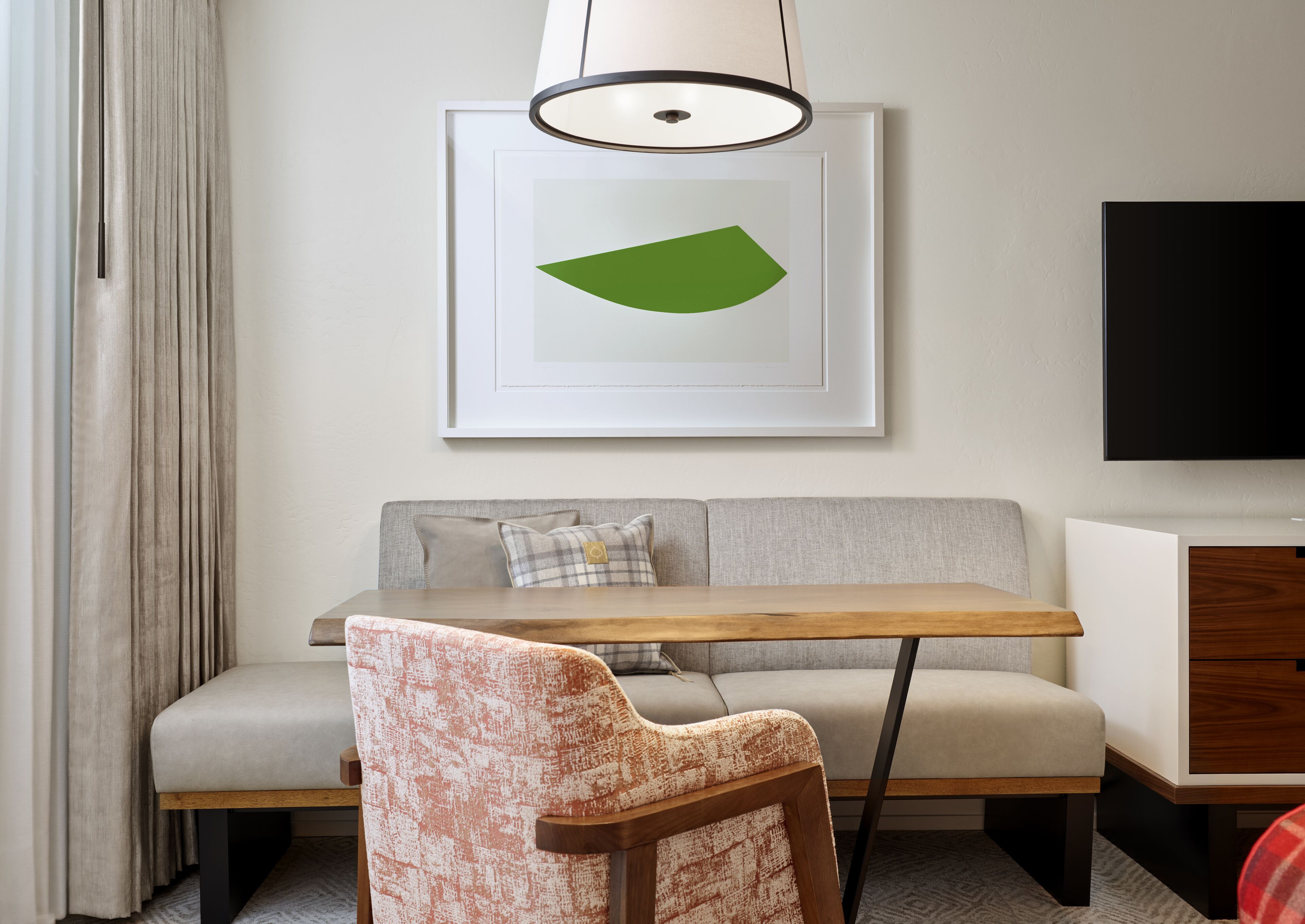 A modern living room with a sofa, a wooden table, a chair, a framed artwork, and a TV.