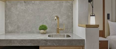 A modern kitchen with a stainless steel sink, a small potted plant, and a microwave above the counter.
