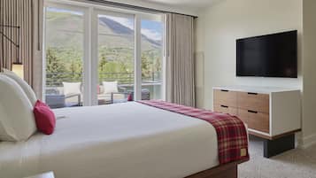 Habitación de hotel con una cama grande, un televisor montado en la pared y un balcón con vistas a la montaña.