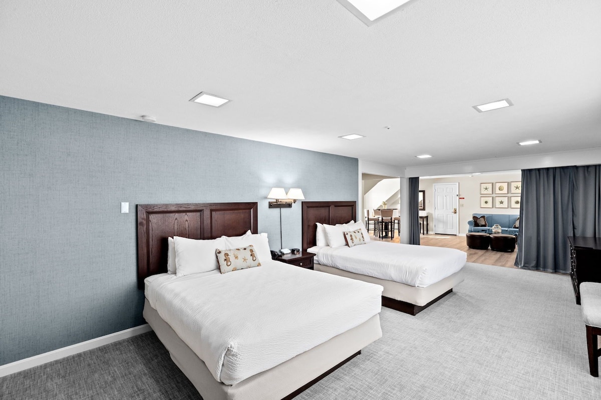 A hotel room with two beds, a desk, and a chair.