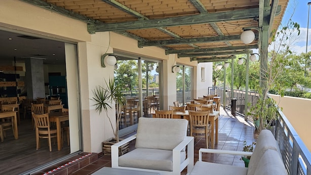 An outdoor patio area with wooden furniture, including sofas and tables, and potted plants. - Hotel YIT Ciudad de Elche (Elche)
