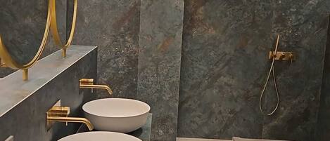 Un baño moderno con dos lavamanos redondos, ducha y tragaluz.