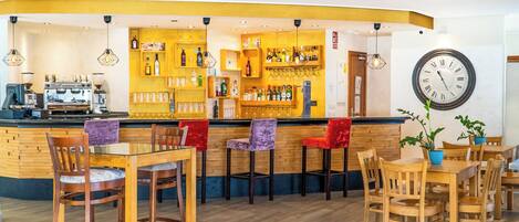 Zona de bar con mostrador, taburetes y un reloj en la pared.