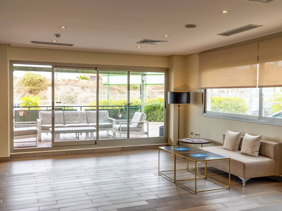 Amplia habitación con un gran ventanal corredero que da a un área exterior con mobiliario de patio.