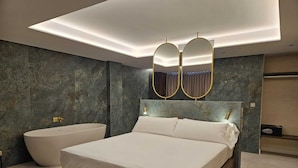 A modern bedroom with a large bed, a bathtub, and a vanity with a mirror. - Hotel YIT Ciudad de Elche (Elche)