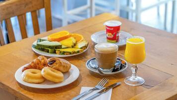 A breakfast setting with croissants, fruit, coffee, and orange juice on a wooden table.