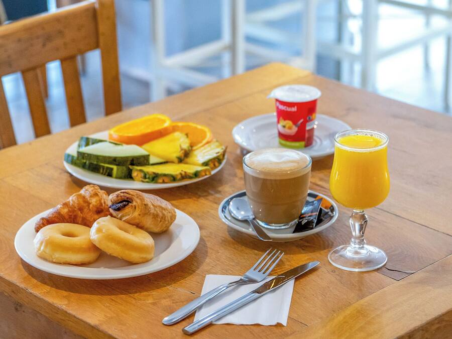 A breakfast setting with croissants, fruit, coffee, and orange juice on a wooden table.