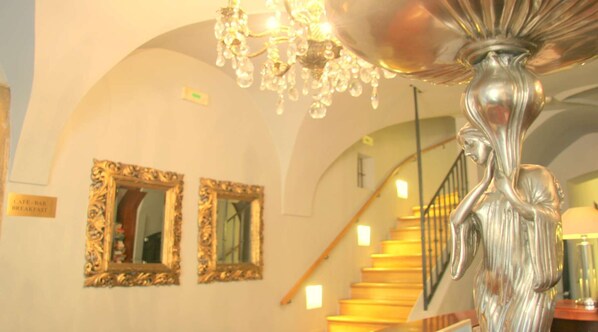Un candelabro, dos espejos decorados y una escalera con barandilla.