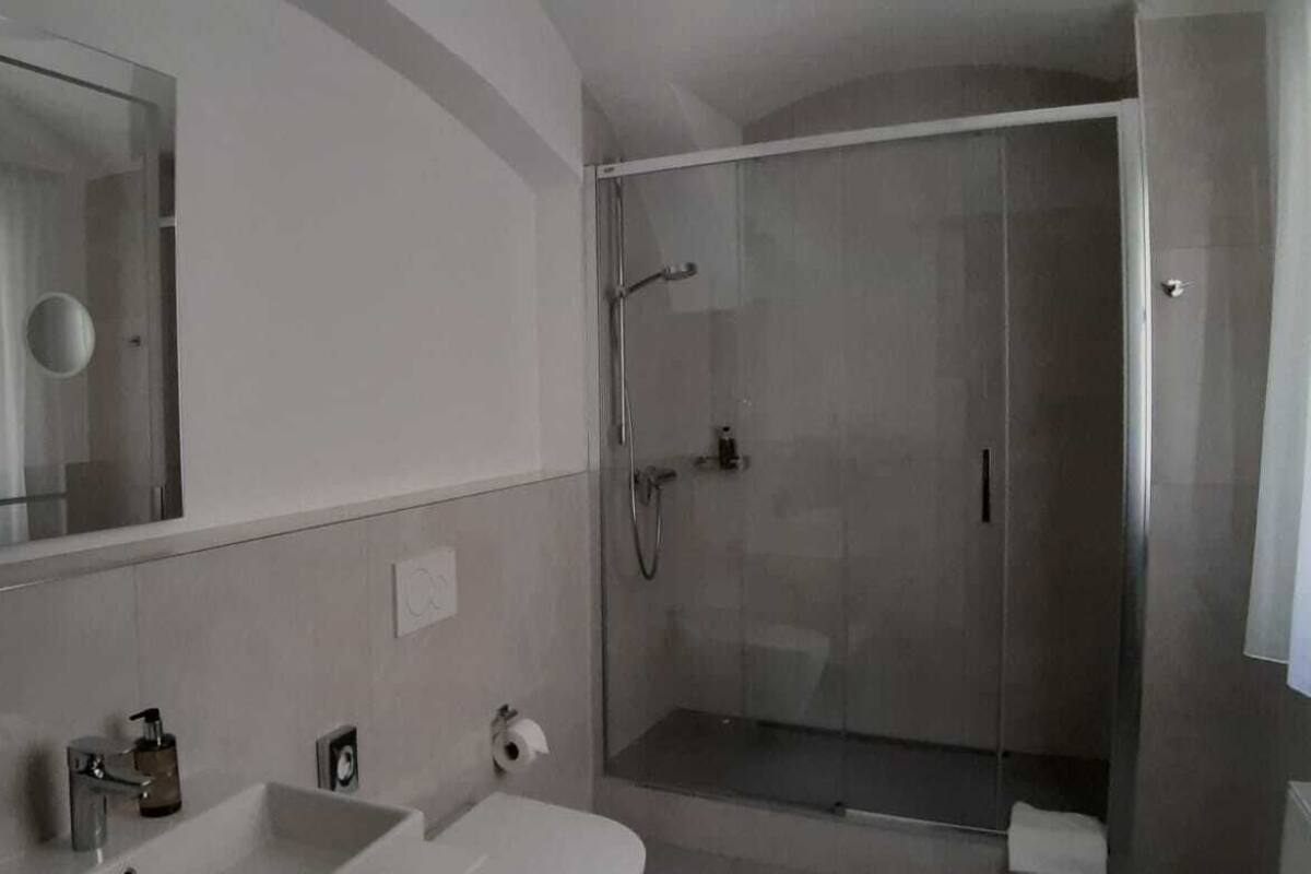 Un baño moderno con un espejo grande, cabina de ducha y lavamanos.