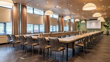 A conference room with a long table, chairs, and large windows.