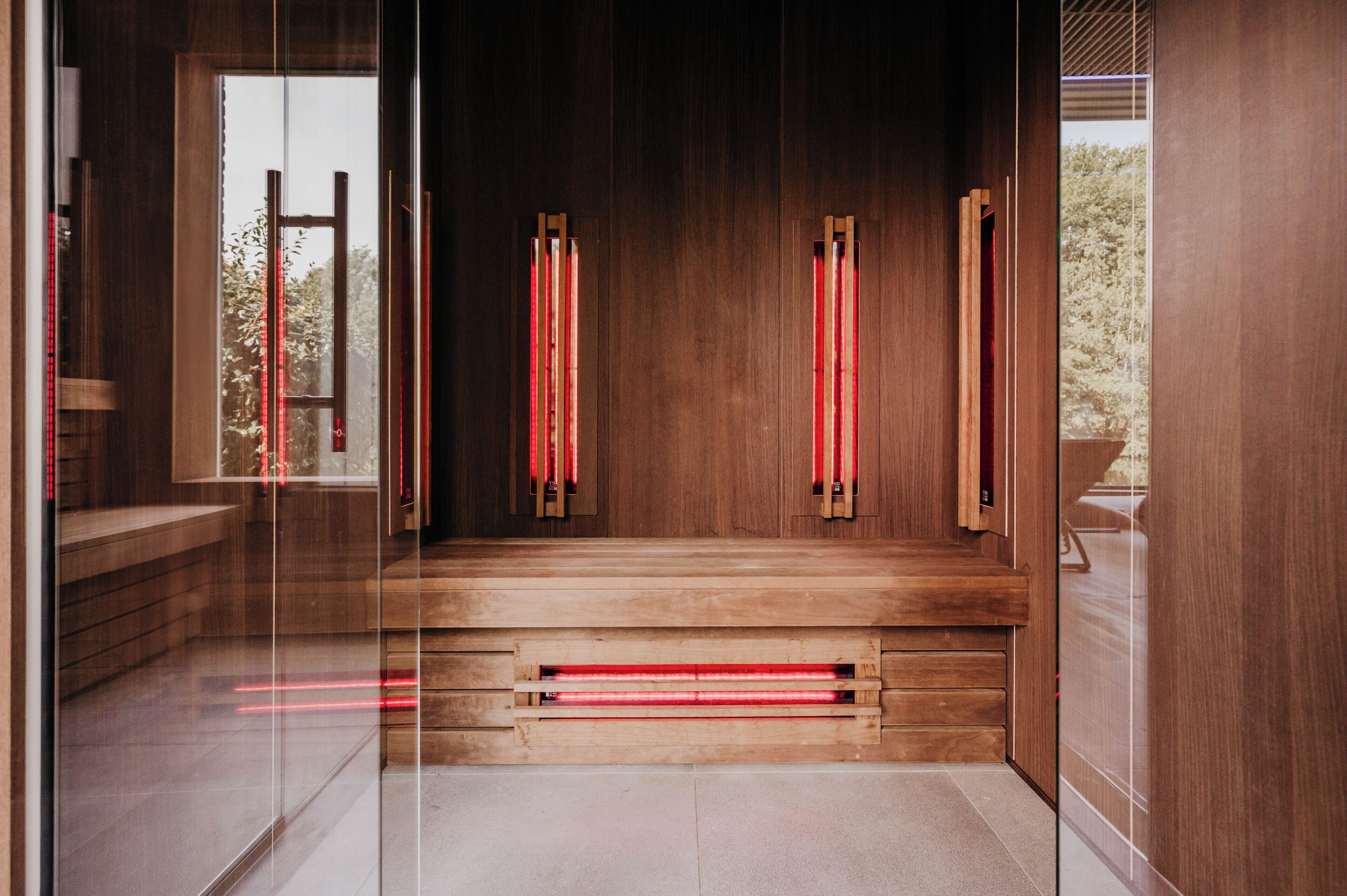 A modern interior with wooden paneling, a glass partition, and a red-lit bench.