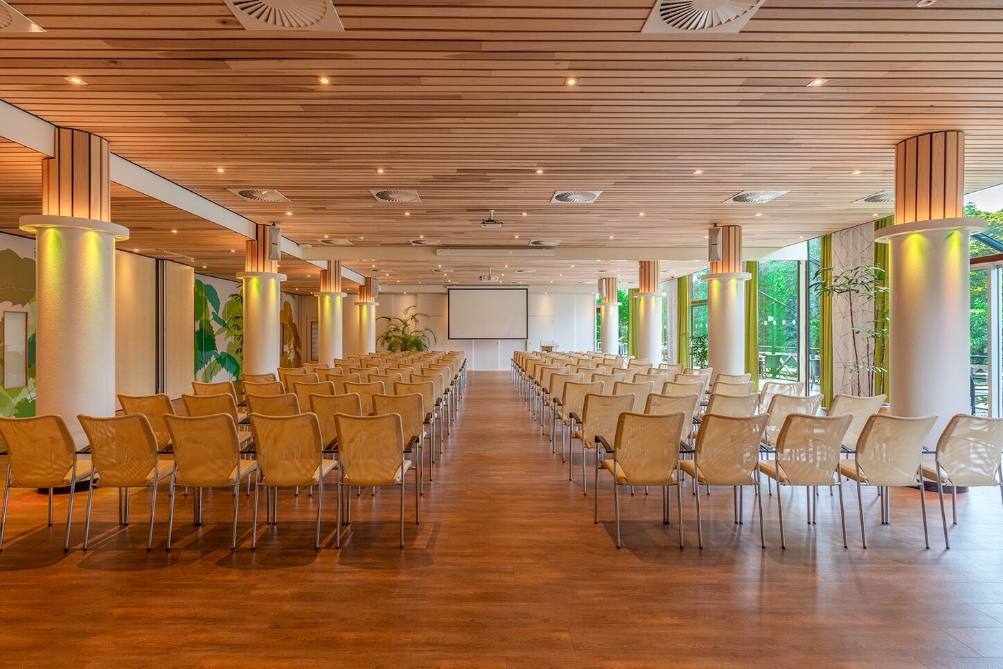 A conference room with rows of chairs, wooden ceiling, and large windows.