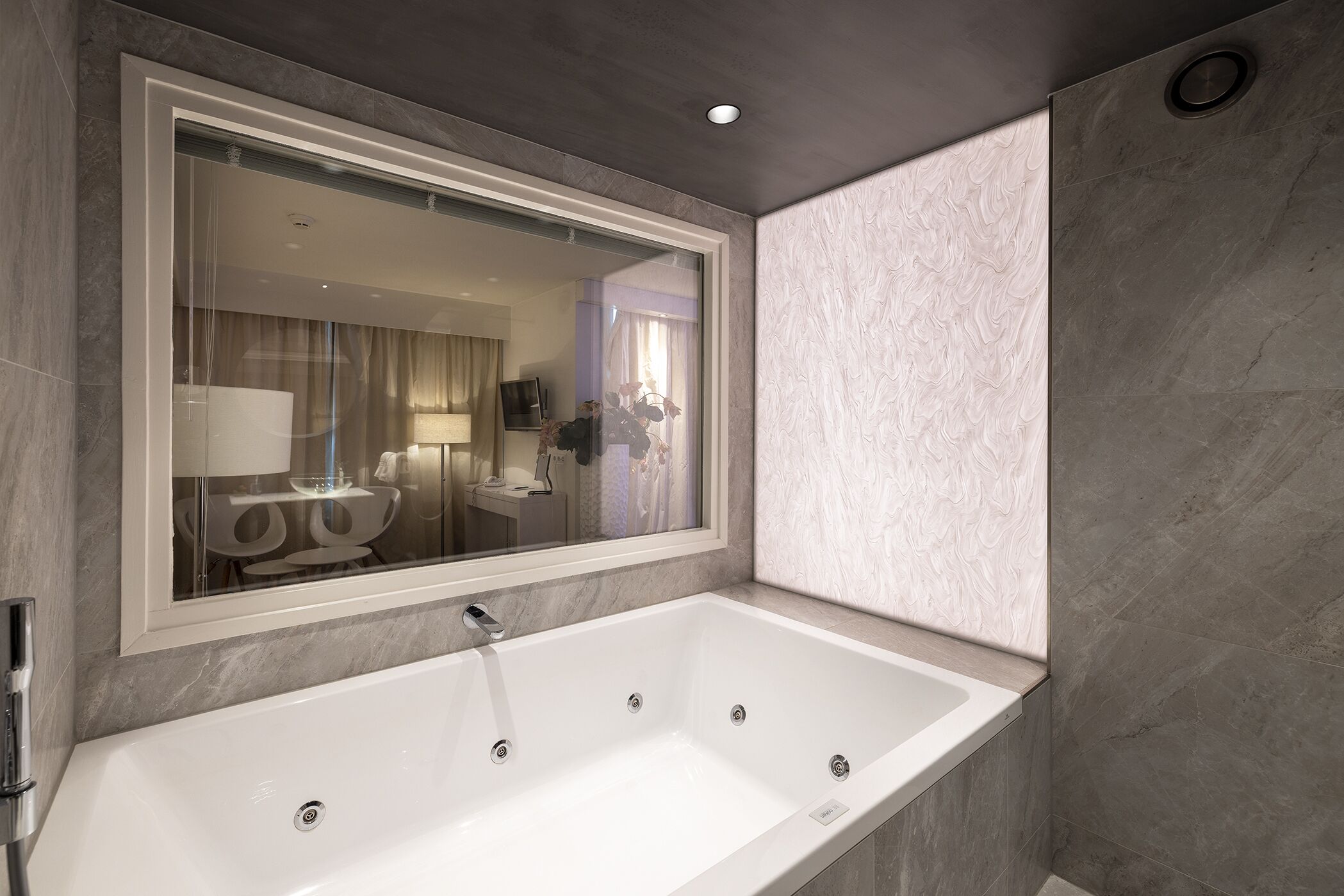 A modern bathroom with a large bathtub, a mirror, and a shower area.