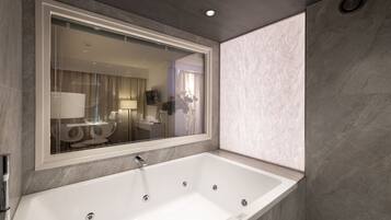 A modern bathroom with a large bathtub, a mirror, and a shower area.