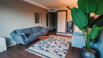 Una sala de estar moderna con un sofá, una mesa de centro, una alfombra, una planta en maceta y un mueble aparador.
