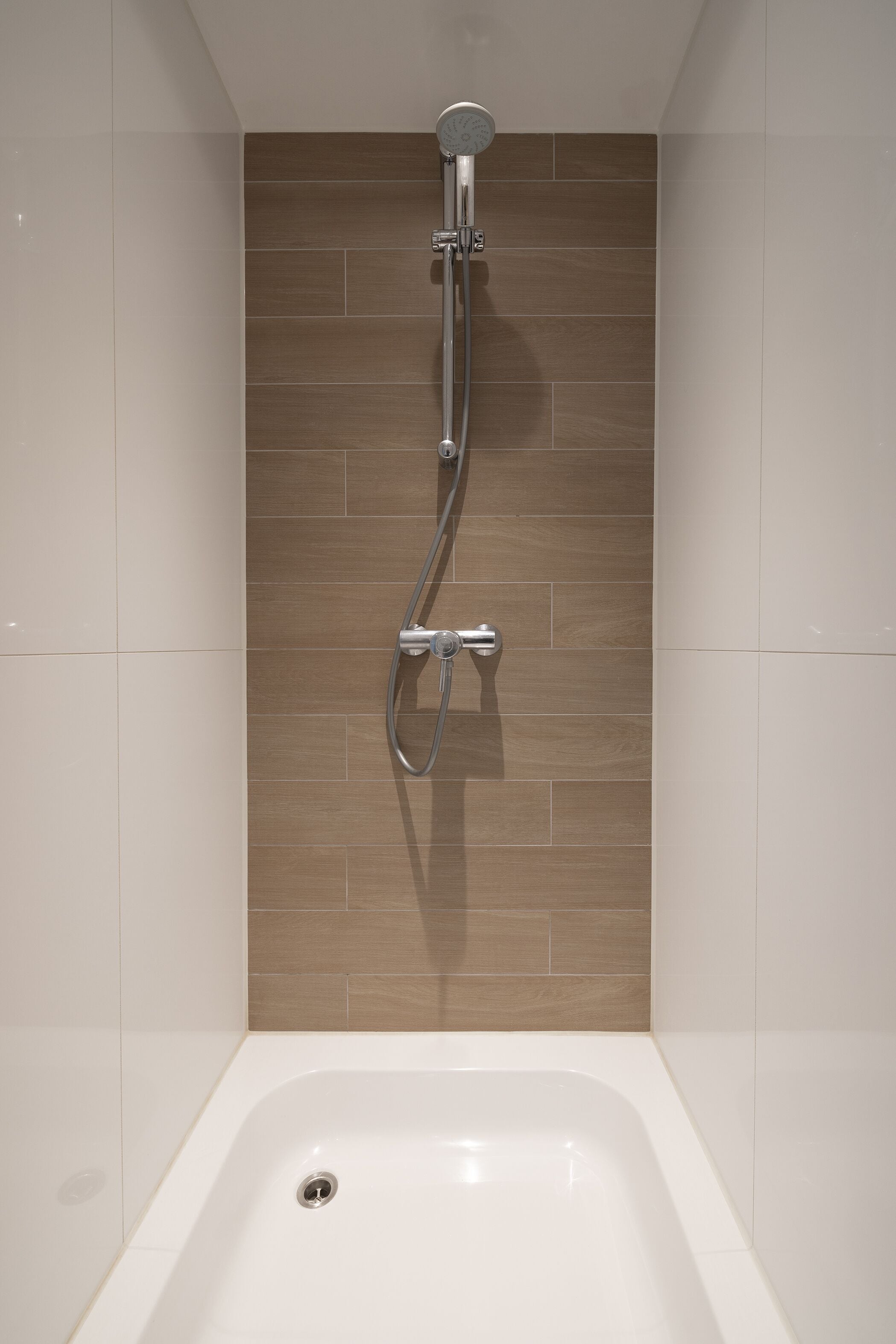 A modern bathroom with a shower, a bathtub, and tiled walls.