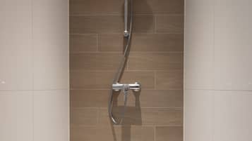 A modern bathroom with a shower, a bathtub, and tiled walls.