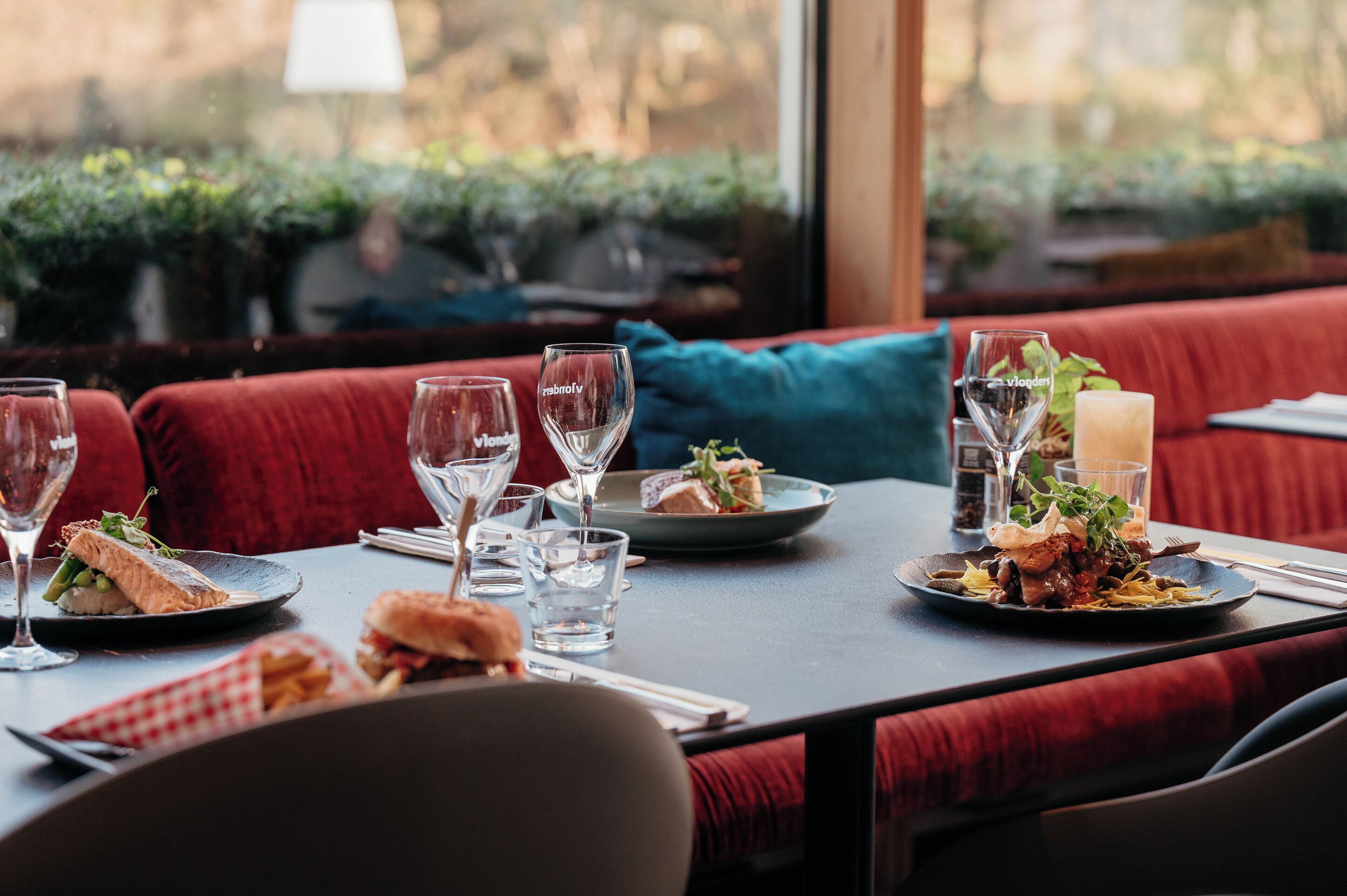 A restaurant table set with plates of food, glasses, and a candle.