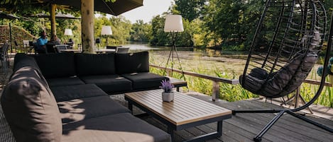 Un espacio al aire libre con sillones, una mecedora y una mesa con lámpara.