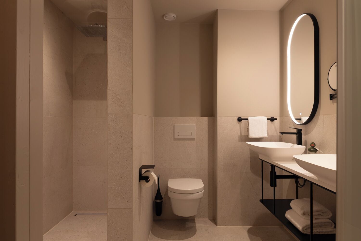 A modern bathroom with a shower, toilet, and dual sinks.