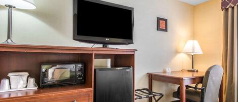 Une chambre d’hôtel équipée d’une télévision à écran plat, d’un four à micro-ondes, d’un réfrigérateur, d’un bureau avec une chaise et d’un lit.