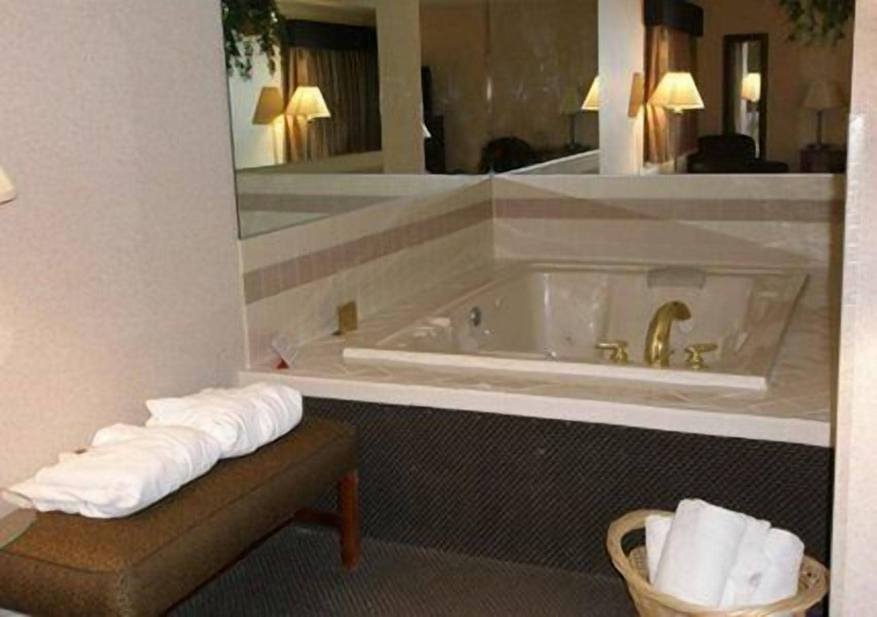 Ein Badezimmer mit einer großen Badewanne, einer Sitzbank und einem Spiegel.