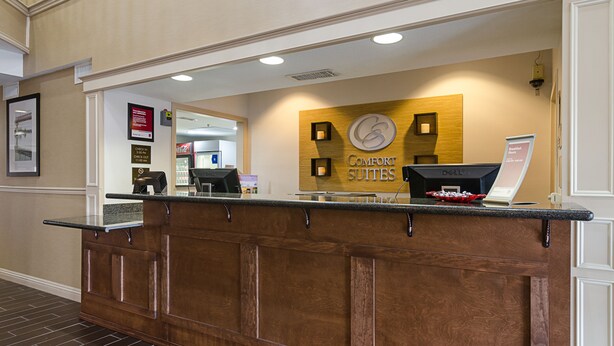 A reception desk with a sign for 'Comfort Suites' and a laptop.