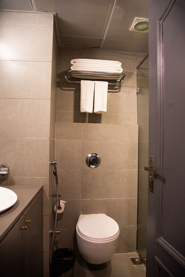 A bathroom with a toilet, a sink, a shower, and a towel rack. - Golden Parkk (Kolkata)