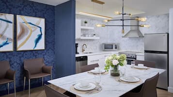 Una cocina moderna equipada con horno, microondas y refrigerador. Hay una mesa de comedor con platos, vasos y un jarrón de flores.
