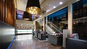 A modern lobby with a staircase, seating areas, and a 'PANTAGES' sign.