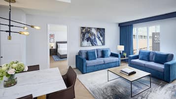 Una sala de estar moderna con un sofá azul, una mesa de centro y una zona de comedor con una mesa de mármol.