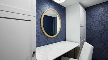 A bathroom with a white vanity, a gold-framed mirror, and blue patterned wallpaper.