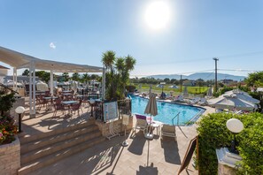 A poolside area with outdoor seating, a pool, and a view of the landscape. - Venus Hotel & Suites (Zakynthos)