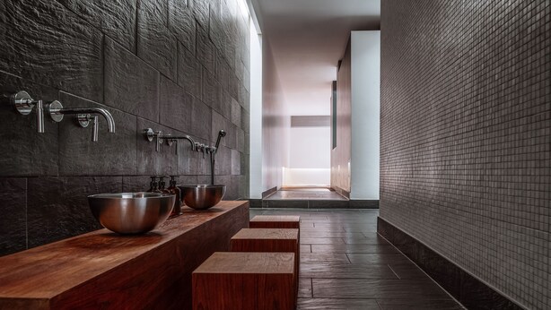 Une salle de bain moderne avec un meuble-lavabo en bois, un grand lavabo en métal et un espace douche épuré.